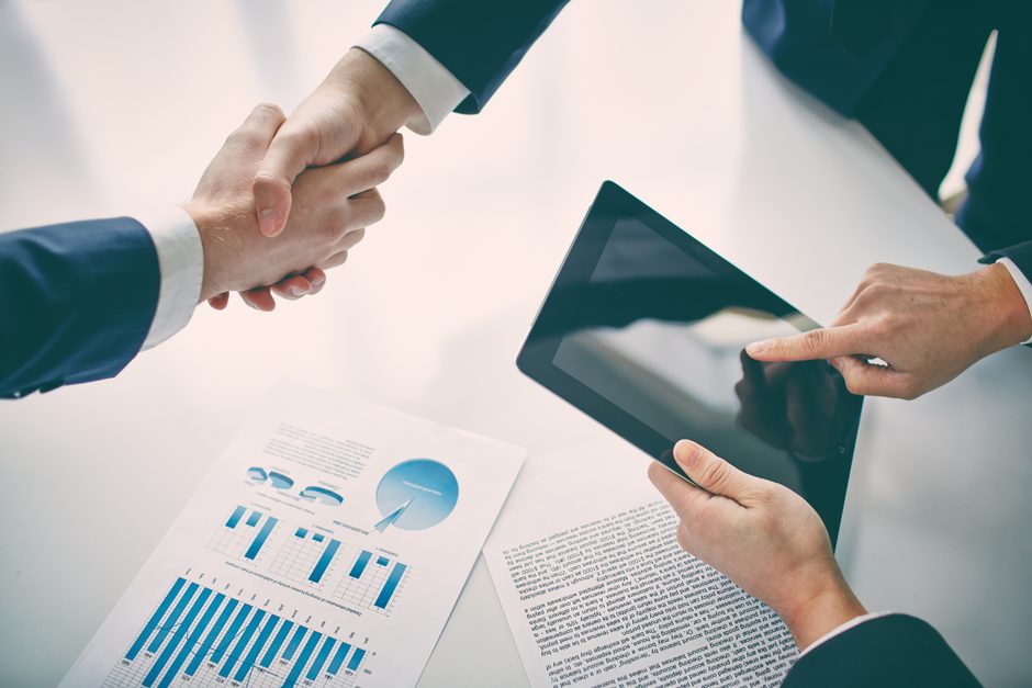 Handshake over a tablet and meeting documents